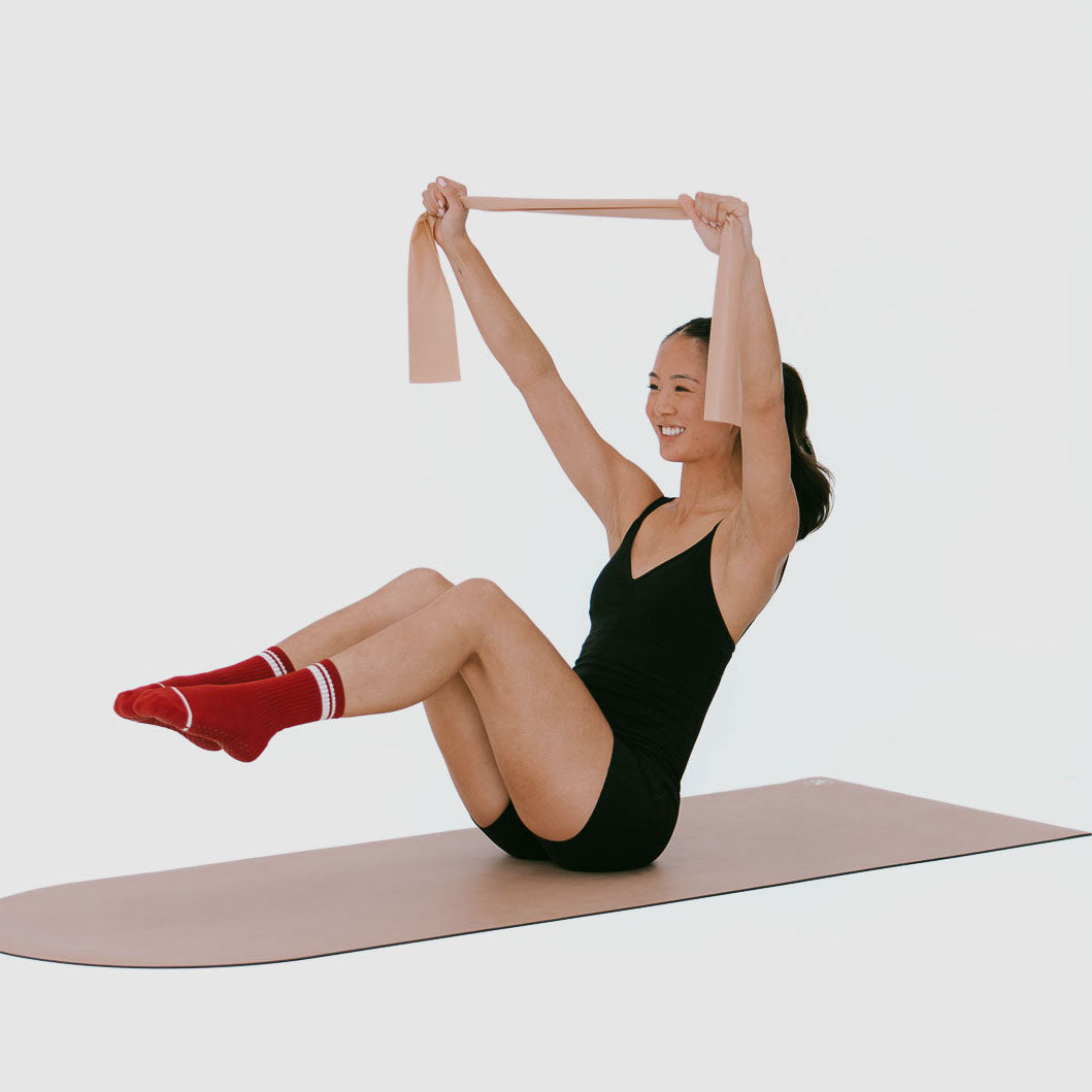 Mocha Stretch Resistance Band used in Pilates core exercise on mat - On Model | Your Reformer