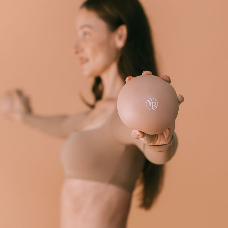 Mocha Pilates Toning Ball Held Toward Camera - Lifestyle Detail | Your Reformer