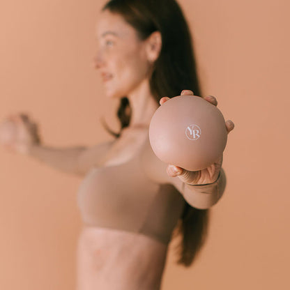 Mocha Pilates Toning Ball Held Toward Camera - Lifestyle Detail | Your Reformer