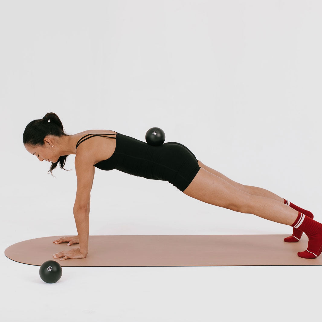 Black Pilates Toning Balls Used in Plank Balance Exercise on Mat - On Model | Your Reformer
