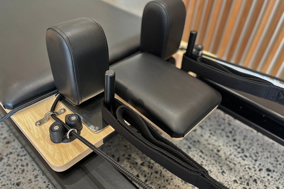 Black Studio X Reformer - Close-up of Wooden Jump Board and Shoulder Blocks | Your Reformer